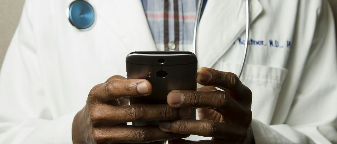 A clinician checking a mobile phone between patients